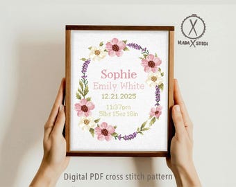 Puede incluir: Un patrón de punto de cruz enmarcado con un diseño de corona floral. La corona rodea el nombre "Sophie", el nombre "Emily White" y la fecha 12.21.2025. El texto también incluye la hora 23:37 y el peso 2,55 kg y la altura 45,72 cm. El marco está sostenido por manos.