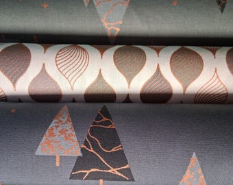 May include: Close-up of several fabric rolls with repeating patterns. The patterns include stylized Christmas trees, ornaments, and teardrop shapes in shades of gray, white, and copper. The fabric appears to be cotton or a similar material.