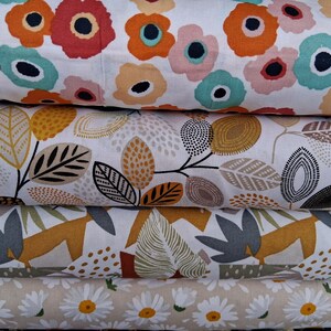 May include: Four different fabric swatches with various patterns. The top swatch features a white background with large orange, pink, and blue floral designs. The second swatch has a white background with brown and yellow leaf patterns. The third swatch has a white background with brown, yellow, and gray leaf patterns. The bottom swatch has a beige background with white daisy flowers.