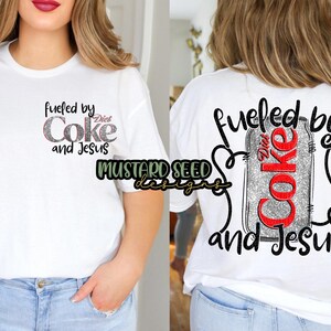 May include: White t-shirt with the text "Fueled by Diet Coke and Jesus" in a glittery design on the front and back. The back features a Diet Coke can graphic. The shirt is a casual, everyday wear item.