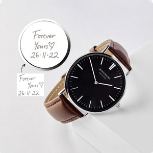 Brown leather wristwatch with a black minimalist face, showing an engraved message on the back reading Forever Yours, 26-11-22 with a heart symbol, featuring handwritten customization