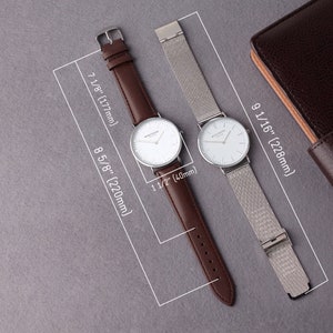 May include: Two wristwatches with white faces and silver hands. The watch on the left has a brown leather band, and the watch on the right has a silver mesh band. Both watches are 1 1/2 inches in diameter.