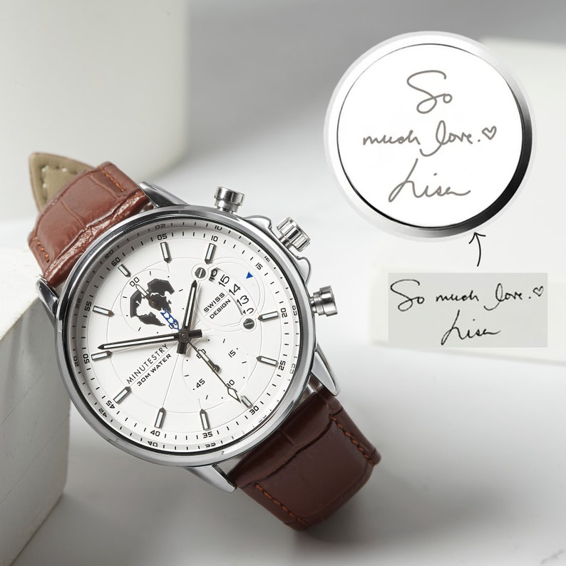 May include: A silver wristwatch with a white face and brown leather band. The watch face features a world map design, a date window, and the text "MINUTESTRY 30M WATER".