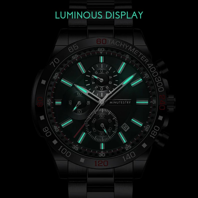 Puede incluir: Un reloj de pulsera cron&oacute;grafo negro con una esfera verde luminosa y detalles rojos. El reloj tiene una escala de taqu&iacute;metro alrededor del borde exterior y las palabras "MINUTESTRY" impresas en la esfera.