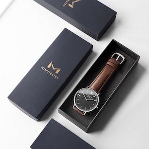 Classic black dial watch with brown leather strap, presented in a branded gift box