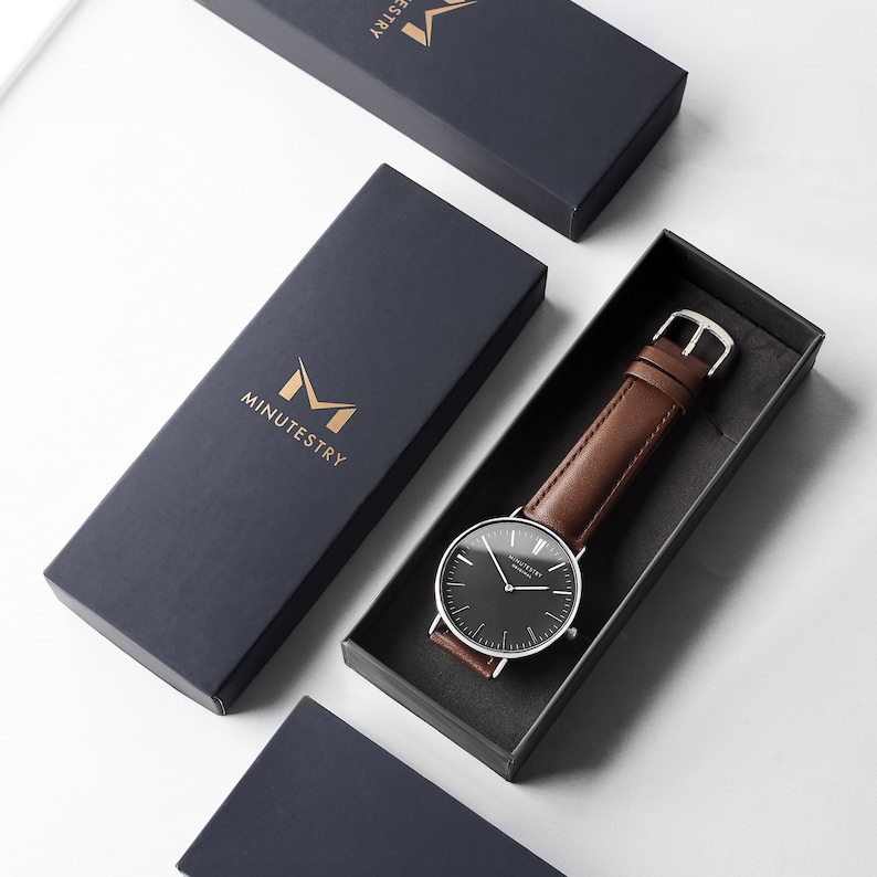 Classic black dial watch with brown leather strap, presented in a branded gift box