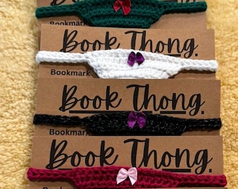 May include: Six crocheted bookmarks with the text "Book Thong" on each. The bookmarks are in different colors, including black, white, green, red, and purple. Each bookmark has a small bow attached to it.
