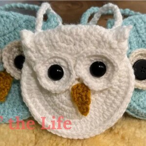 May include: Three crocheted owl purses, one white, one light blue and one teal blue. Each purse has black button eyes and a yellow beak.