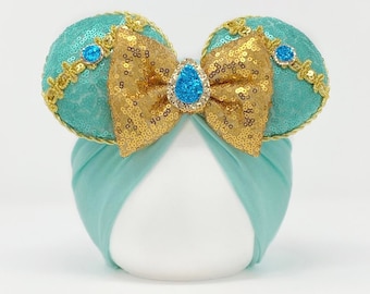 May include: Turquoise blue headband with gold sequin ears and a gold bow with a blue jewel in the center.