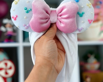 May include: White headband with a pink bow and colorful Mickey Mouse embellishments.