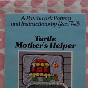 May include: A patchwork pattern and instructions for a turtle-shaped mother's helper. The pattern is for a 34 inch by 26 inch finished project. The image shows a colorful turtle with pockets and a smaller turtle with a ruffle trim.