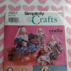 May include: A Simplicity Crafts magazine pattern for making bunny dolls. The pattern includes instructions for making 12 different bunny dolls, each with a unique design. The dolls are shown in various poses, wearing different outfits and accessories. The pattern number is 7651.