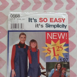 May include: A sewing pattern for a denim pinafore dress with a red turtleneck. The pattern is for sizes XS-XL and is available in sizes 3-8. The pattern is from Simplicity and is called "It's SO EASY it's Simplicity".
