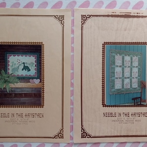May include: Two brown framed cards with the text "NEEBLE IN THE HAYSTACK" and contact information. The left card shows a framed quilt with a pink background and two green animals kissing. The right card shows a framed quilt with a blue background and a patchwork of pink squares.