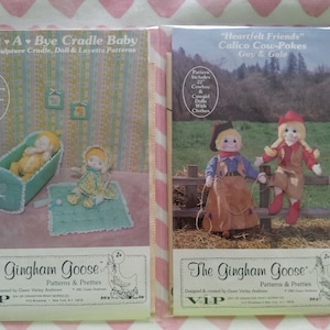 May include: Two vintage sewing patterns from The Gingham Goose. The first pattern is for a soft sculpture cradle, doll, and layette. The second pattern is for a cowboy and cowgirl doll. Both patterns feature illustrations of the finished dolls.