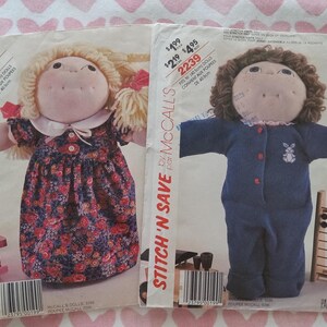 May include: Two McCalls Stitch 'N Save sewing pattern envelopes for 16 inch dolls. The left envelope features a blonde doll in a floral dress. The right envelope features a brown-haired doll in a blue jumpsuit with a white rabbit graphic.
