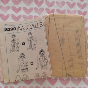 May include: Vintage McCall's sewing pattern for a blazer, featuring illustrations of the finished garment. The pattern is labeled 8290 and includes multiple views. The pattern is accompanied by a folded piece of tan paper with pattern pieces.