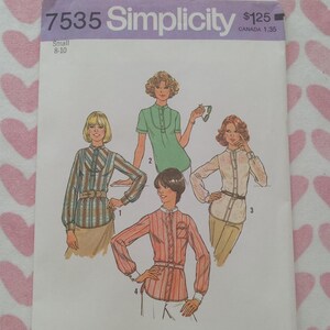 Puede incluir: Un patrón de costura Simplicity vintage, número 7535, con ilustraciones de cuatro diseños de blusas. El patrón es para tallas pequeñas 8-10. La portada tiene un patrón de corazones rosas y blancos.