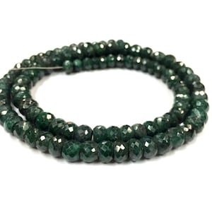 May include: A strand of dark green faceted gemstone beads. The beads are round and have a smooth, polished finish.