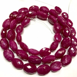 以下が含まれることがあります： 深紅色のファセットカットされたルビービーズのストランド。ビーズは楕円形で、光沢のある仕上げになっています。