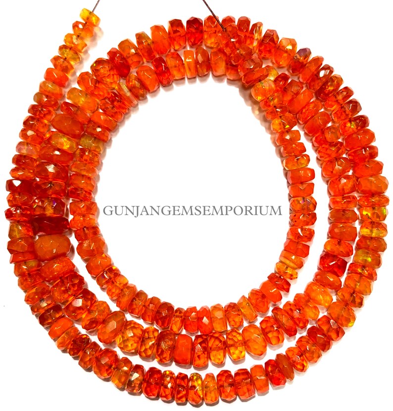 Op de afbeelding: Een streng oranje edelsteen kralen. De kralen zijn gefacetteerd en hebben een licht onregelmatige vorm. De kralen zijn geregen op een dunne draad en zijn klaar om te worden gebruikt voor het maken van sieraden.