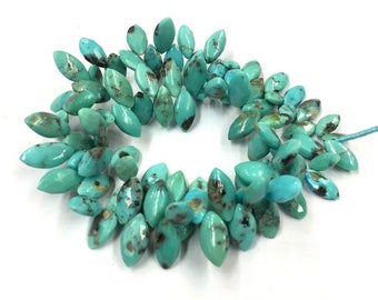 May include: A strand of turquoise gemstone beads in a marquise shape. The beads are a light blue-green colour with brown and black markings.