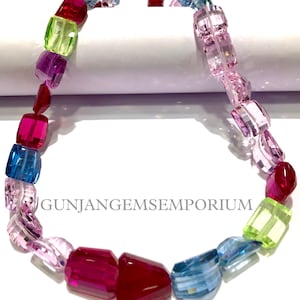 Può includere: Una collana di pietre preziose colorate con perline sfaccettate in tonalità di rosa, blu, verde e rosso. La collana è realizzata con pietre preziose naturali ed è perfetta per aggiungere un tocco di colore a qualsiasi outfit.