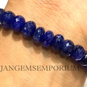 Op de afbeelding: Een blauwe edelsteen armband met gefacetteerde kralen. De armband zit om een pols.