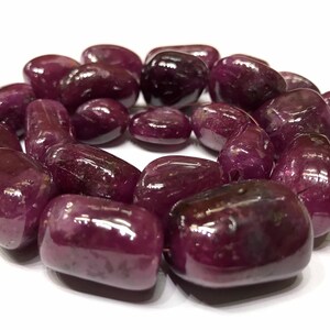 Peut inclure: Un brin de perles de pierres précieuses violettes lisses et polies. Les perles sont de forme ovale et ont une finition brillante.