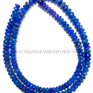 May include: A strand of blue opal beads, each bead is faceted and has a slightly different shade of blue. The beads are strung on a wire and are ready to be used for jewelry making.