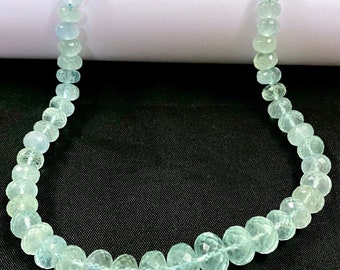 May include: A strand of light blue aquamarine beads, each bead is faceted and has a slightly rounded shape.