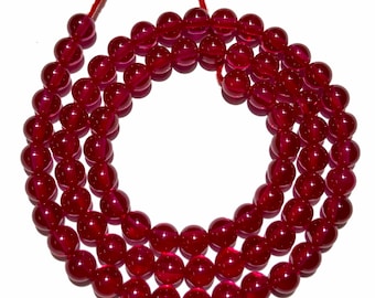 May include: A strand of deep red gemstone beads, strung on a red cord. The beads are round and smooth, with a glossy finish.