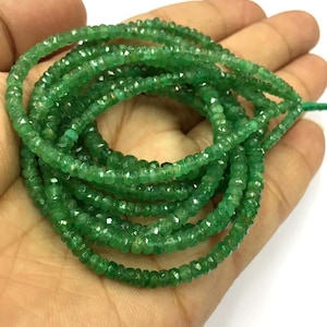 May include: A strand of emerald green gemstone beads. The beads are faceted and have a slightly irregular shape. The beads are strung on a clear thread.