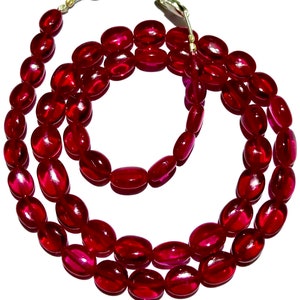 Puede incluir: Un collar de piedras preciosas rojas con cuentas de forma ovalada. El collar está hecho de piedras pulidas y lisas y tiene un cierre de plata.