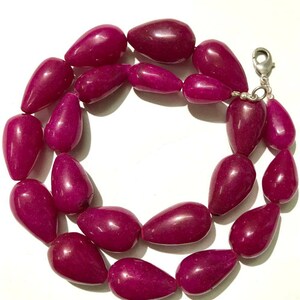 Puede incluir: Una hebra de cuentas de piedras preciosas de color rosa intenso, cada cuenta tiene forma de lágrima. Las cuentas están enhebradas en una cadena de plata con un cierre de plata.