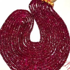 May include: A strand of deep red ruby beads, faceted and strung on a thin cord. The beads are small and uniform in size, creating a smooth and elegant look. The strand is long and can be used for making jewelry or other crafts.