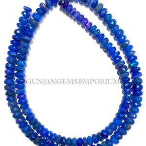 May include: A strand of blue opal beads, each bead is faceted and has a slightly different shade of blue. The beads are strung on a wire and are ready to be used for jewelry making.