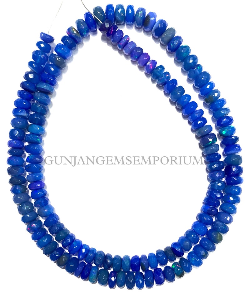 May include: A strand of blue opal beads, each bead is faceted and has a slightly different shade of blue. The beads are strung on a wire and are ready to be used for jewelry making.
