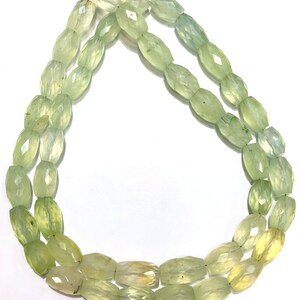 May include: A strand of light green faceted gemstone beads. The beads are oval shaped and have a translucent appearance.
