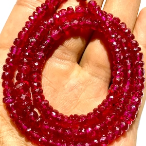 May include: A strand of deep red ruby beads, faceted and polished, strung on a wire. The beads are approximately 4mm in diameter and have a rich, vibrant colour.