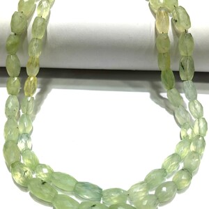 May include: A strand of light green gemstone beads, likely aventurine, with a faceted oval shape. The beads are strung on a clear thread and are arranged in a double row.