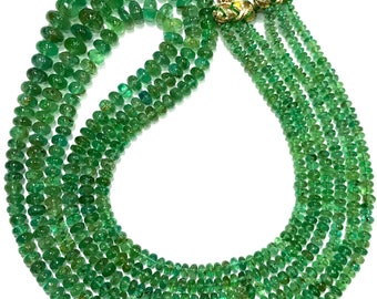 Könnte beinhalten: Eine Kette aus smaragdgrünen Edelsteinperlen, auf einem goldenen Faden aufgefädelt, mit einem Quasten an jedem Ende. Die Perlen sind rund und haben eine glatte, polierte Oberfläche.