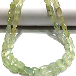May include: A strand of light green gemstone beads, each bead is faceted and oval shaped.