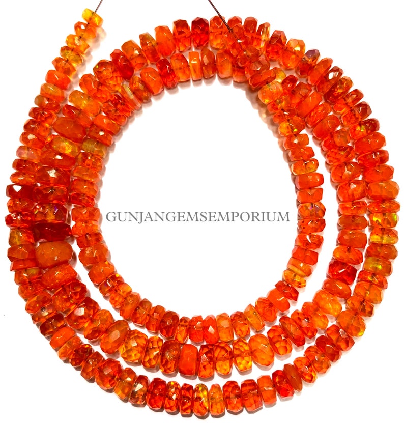 Op de afbeelding: Een streng oranje edelsteen kralen. De kralen zijn gefacetteerd en hebben een licht onregelmatige vorm. De kralen zijn geregen op een dunne draad en zijn klaar om te worden gebruikt voor het maken van sieraden.