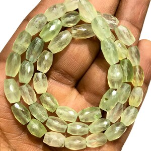 May include: A strand of light green faceted gemstone beads. The beads are oval shaped and have a smooth, polished finish.
