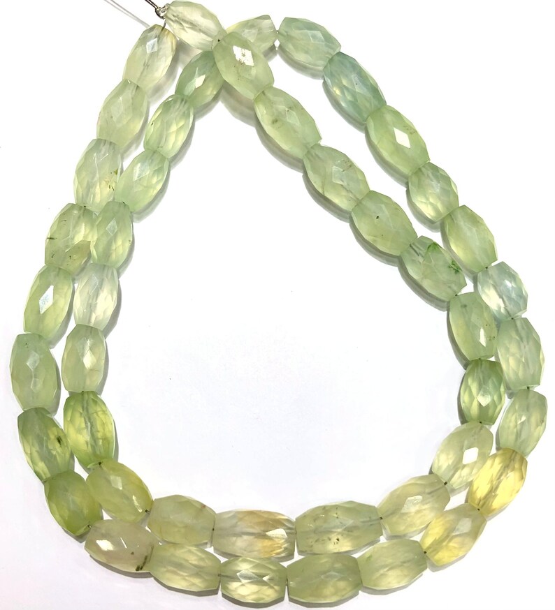 May include: A strand of light green faceted gemstone beads. The beads are oval shaped and have a translucent appearance.