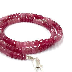 Puede incluir: Un collar de piedras preciosas rosa y rojo con un cierre de plata. El collar está hecho de cuentas facetadas y mide aproximadamente 45 cm de largo.