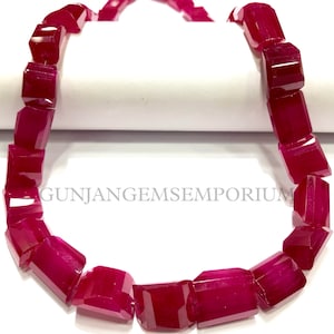 Può includere: Una collana di perle di pietre preziose rosso scuro, ogni perla è sfaccettata e ha una forma rettangolare. Le perle sono infilate su un cordoncino bianco e sono disposte in un motivo circolare. L'immagine è etichettata "GUNJANGEMSEMPORIUM".