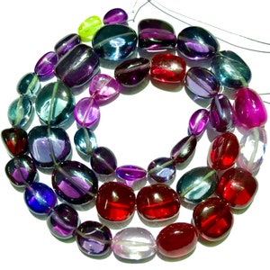 May include: A strand of colourful gemstone beads, featuring shades of purple, red, blue, and green. The beads are oval-shaped and have a smooth, polished finish.