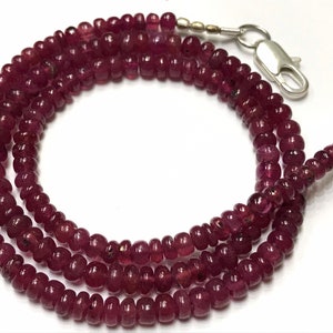 May include: A necklace of small, round, deep red beads. The beads are strung together, creating a multi-strand design. The necklace is fastened with a silver clasp.